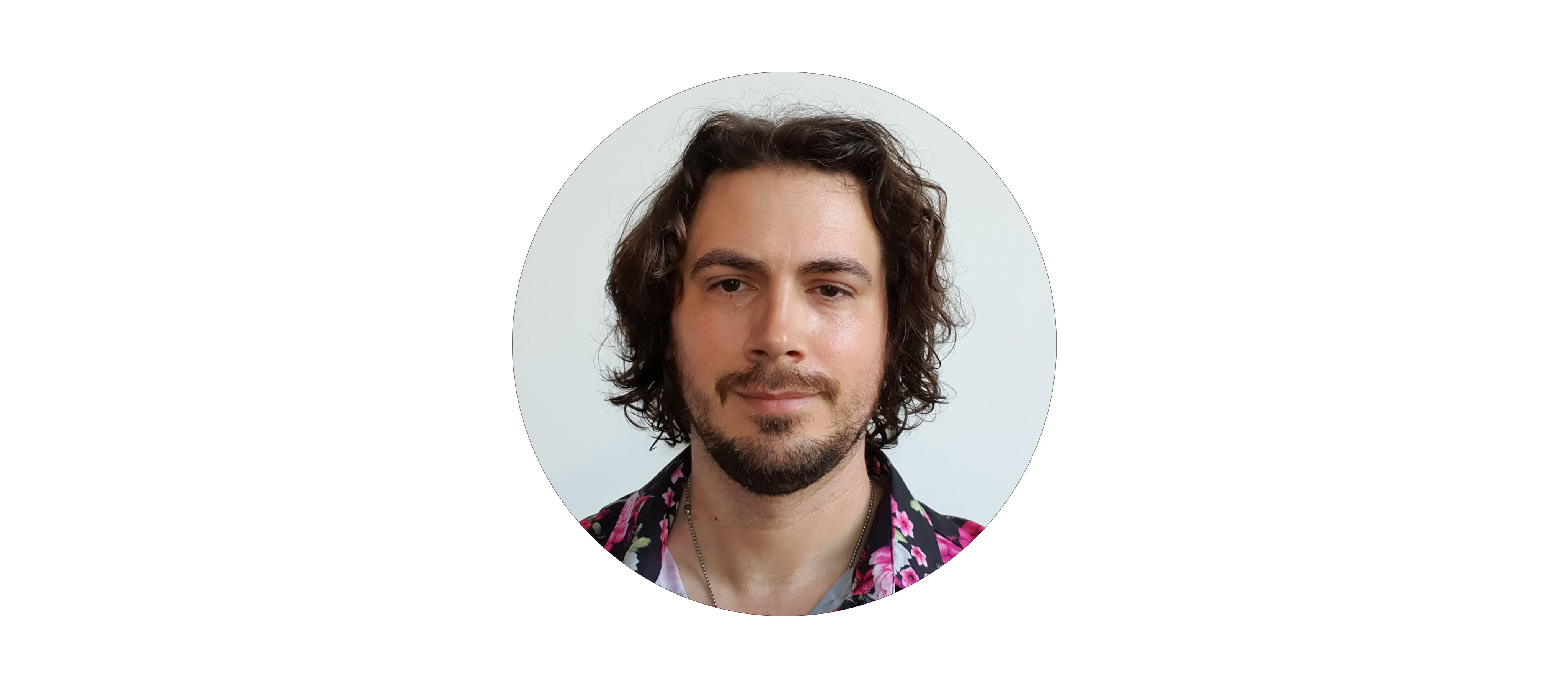 Head shot of Chris Gibson, young male, brown hair short stubble smiling in grey suit