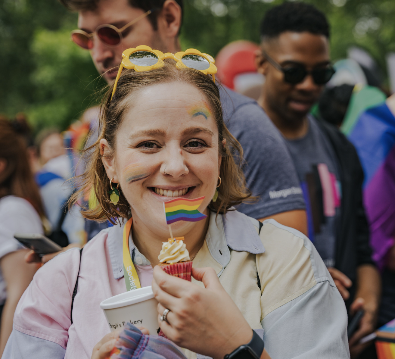 Amanda holding a rainbow cupcake with the decoration LGBTQ+ flag
